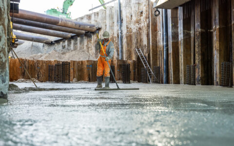 Medewerker van de aannemer maakt het gestorte beton glad.