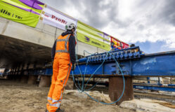 Medewerker staat naast de rails waarover het dak van de onderdoorgang zal schuiven. De rails en betondekken zijn een stuk groter dan de medewerker.