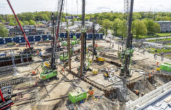 Drone-foto van de machines die de damwanden en buispalen in de grond brengen.